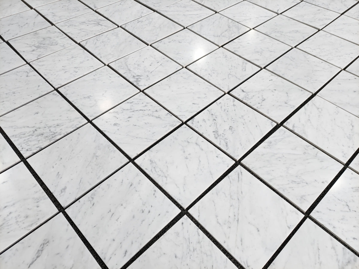 Carrara White Gioia marble 12×12 tiles dry-laid for color and veining selection.