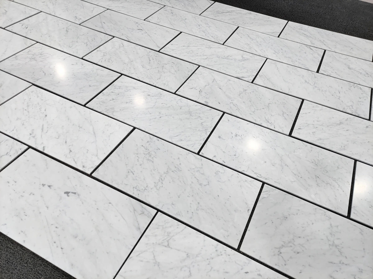 Carrara White Gioia marble 18×36 tiles dry-laid for natural color and veining selection.