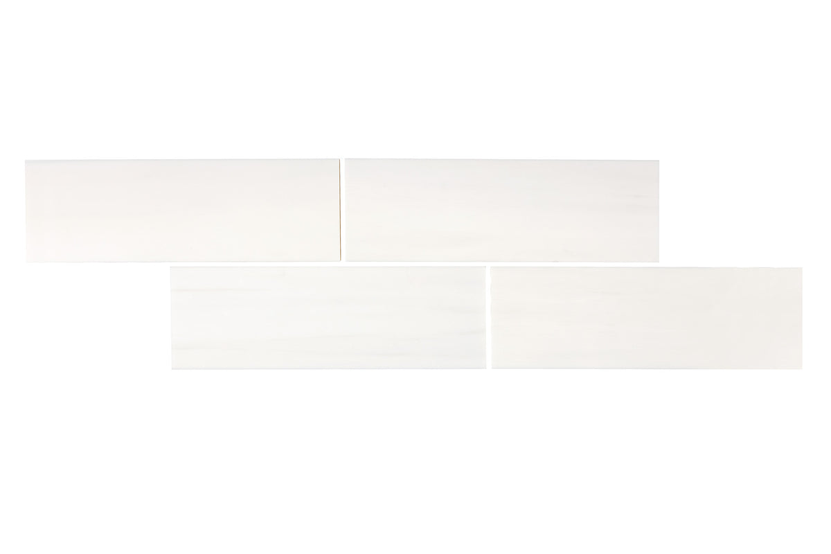 Bianco Dolomite marble 2×8 subway tiles laid in a brick pattern, white with soft gray veining.