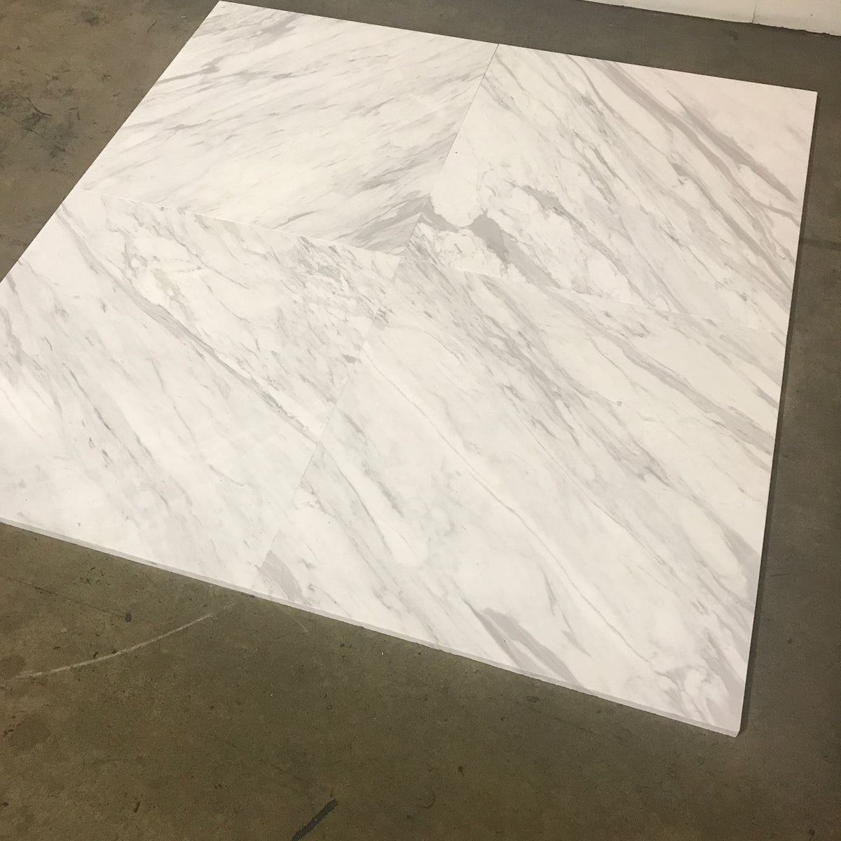 Selection of Calacatta Supreme marble 24×24×¾ polished tiles with natural gray veining.