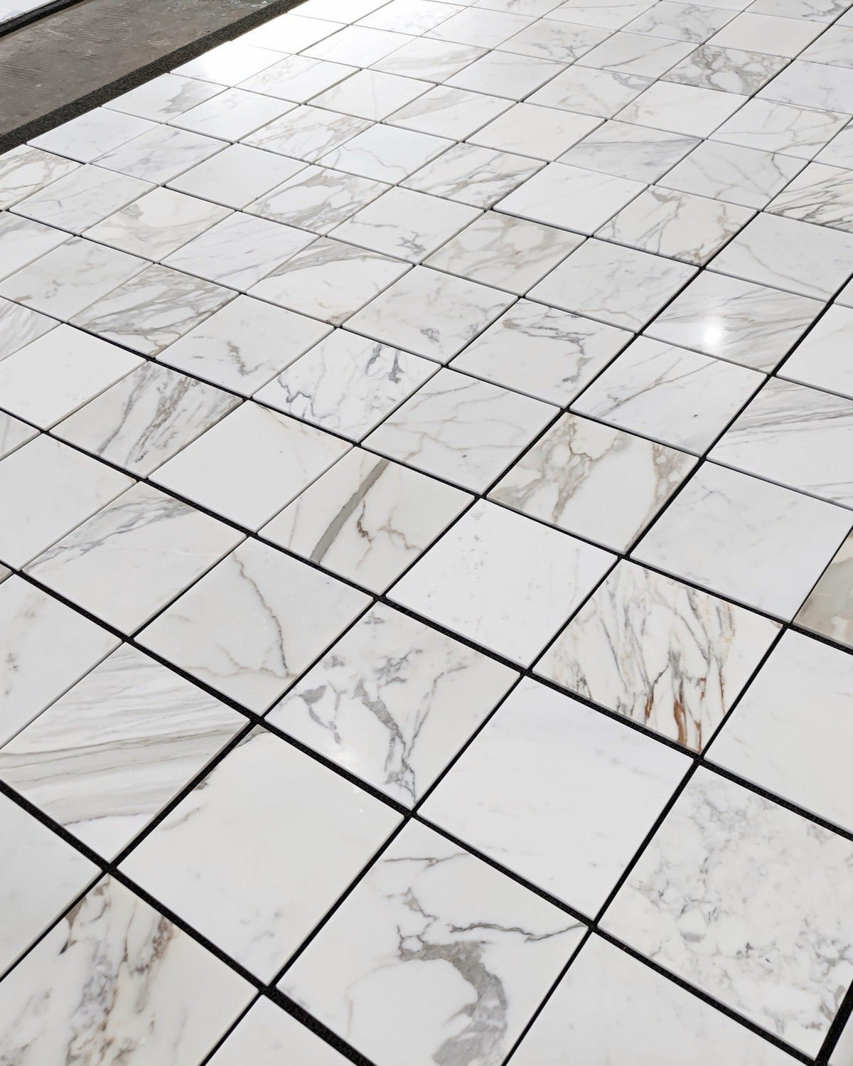Calacatta Gold 12×12 marble tile with luxurious gold veining, perfect for high-end interiors. Available in honed or polished finish for sophisticated style.