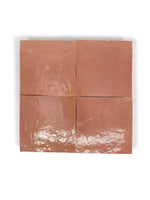 Four square terracotta zellige tiles in a deep red color with a glossy finish, showing handcrafted irregular edges.
