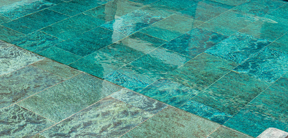 Close-up of SeraPool Natural Verde Guatemala porcelain pool tile under water showing the stone-like green surface