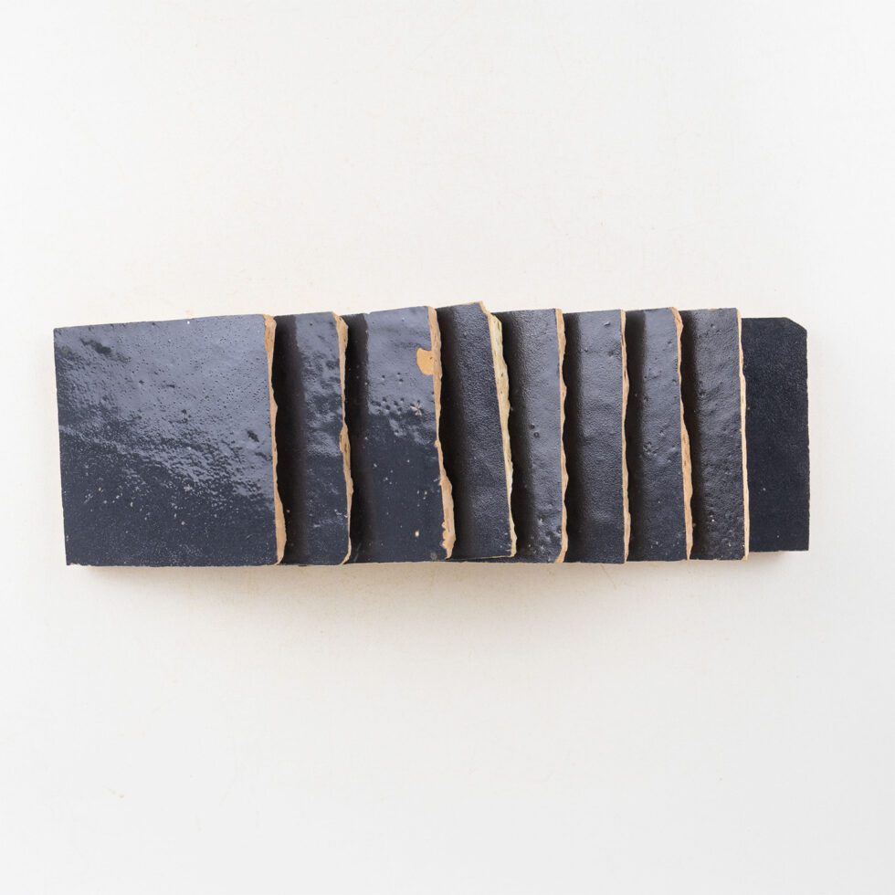 Rectangular block of navy blue zellige tiles with wavy edges on a white background