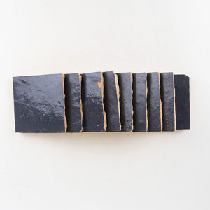 Rectangular block of navy blue zellige tiles with wavy edges on a white background