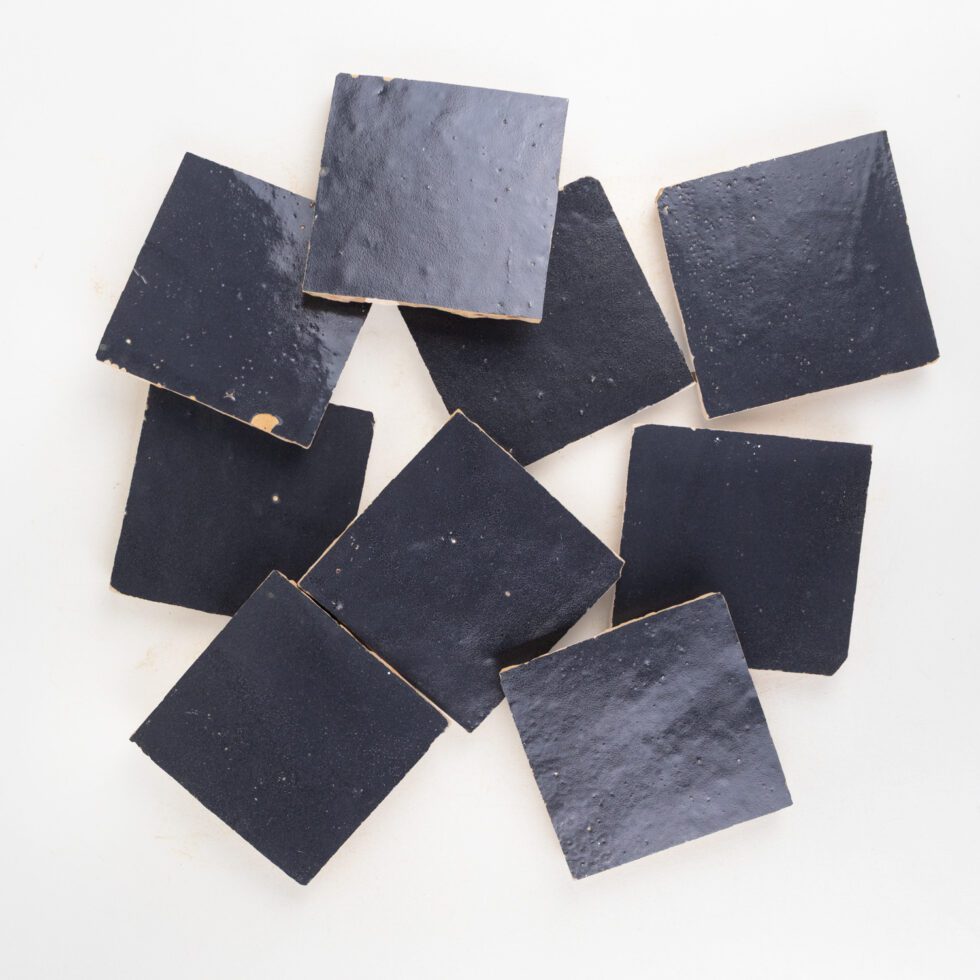 Nine indigo blue square zellige tiles on a white background