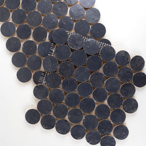 Close-up of dark blue circular zellige mosaic tiles arranged in a pattern on a white background