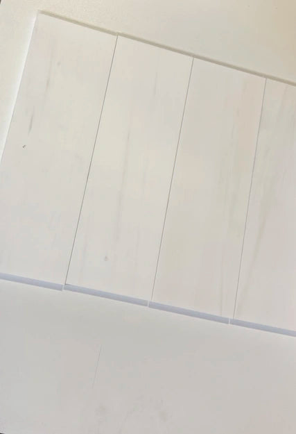 Bianco Dolomite 4x12 subway tiles aligned in a sleek vertical layout, showcasing their bright white tones and smooth finish.