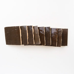 Row of dark brown square zellige tiles on a white background. Made in Morocco.