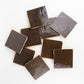 Dark brown square hand-made zellige tiles on a white background
