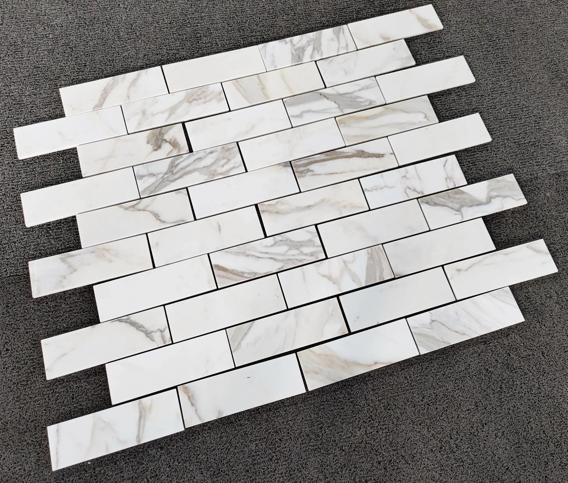 Calacatta Gold Italian Marble subway tile pattern on a dark surface