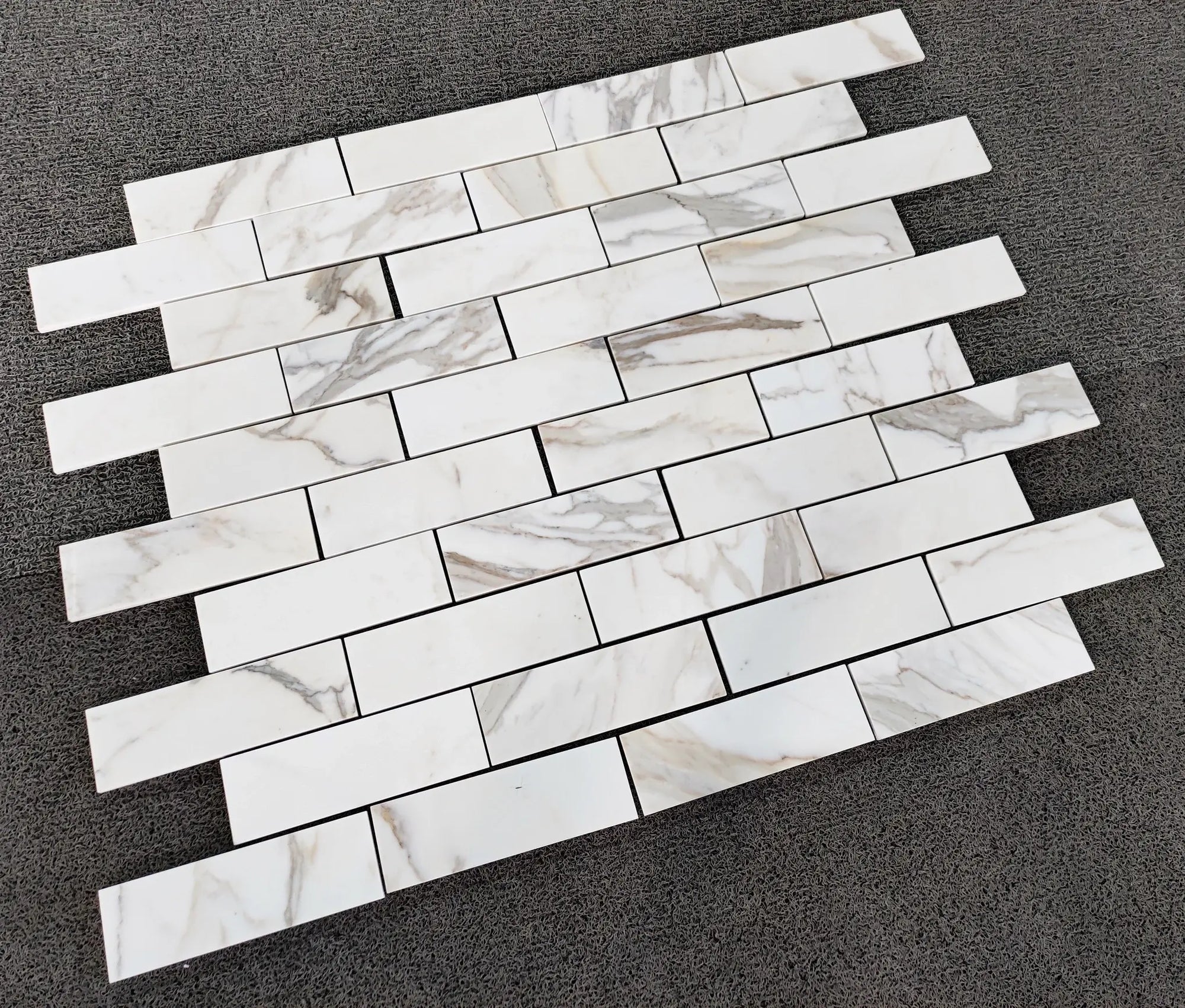 Calacatta Gold Italian Marble subway tile pattern on a dark surface