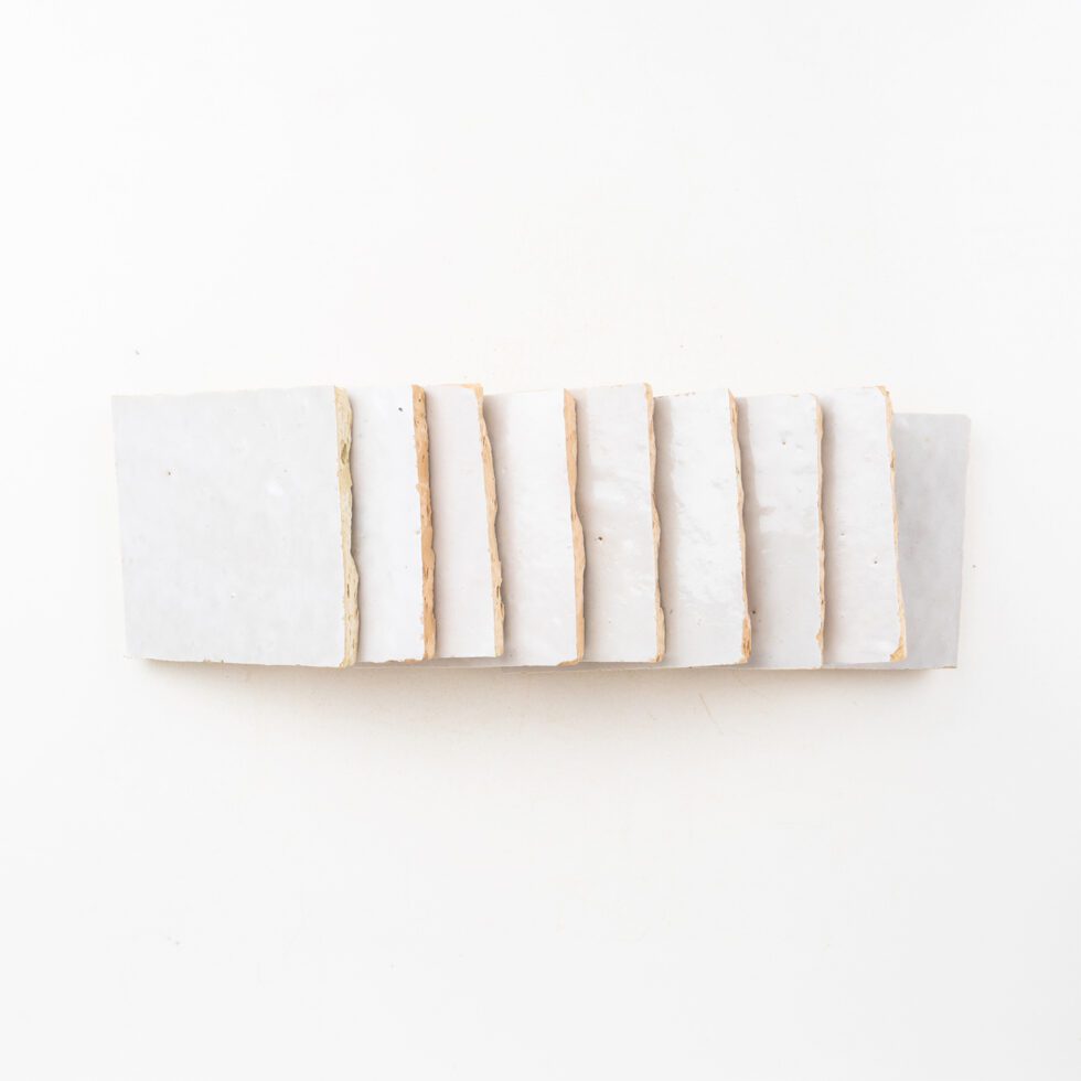 Square white zellige tiles with gold edge on a white background
