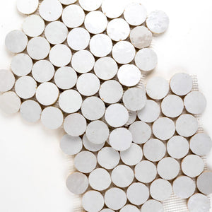 Close-up of white circular zellige mesh-mounted tiles arranged in a pattern on a white background