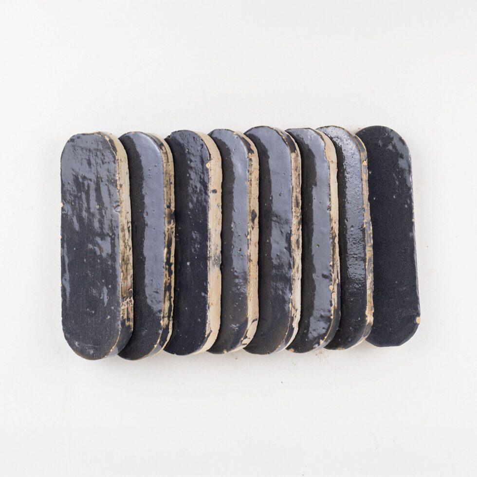 Row of indigo color oval zellige tiles on a white background