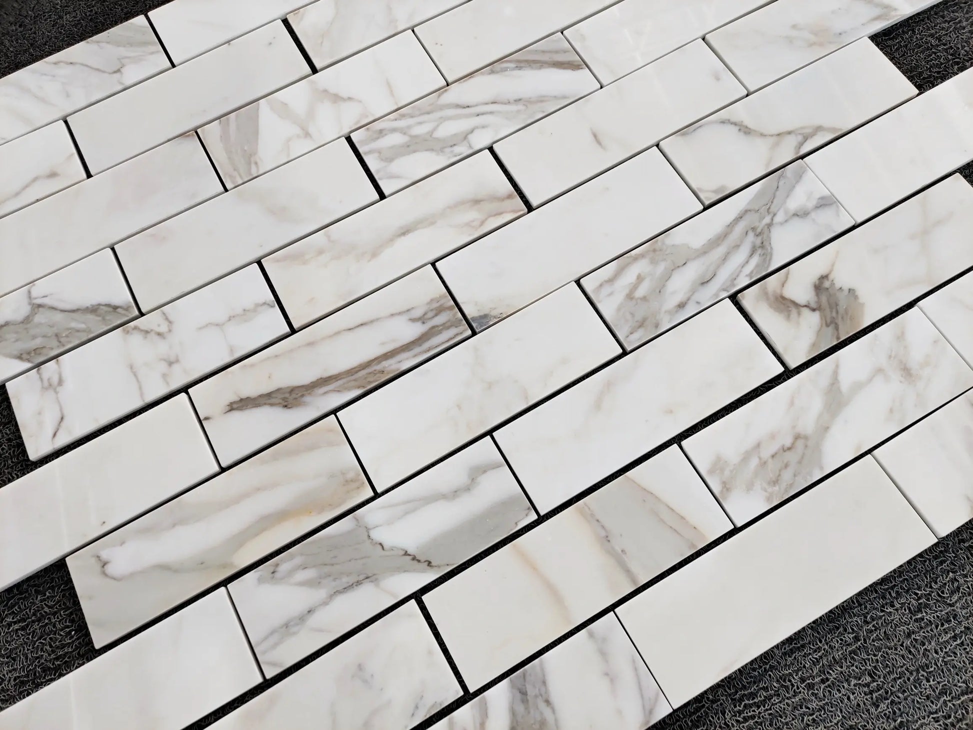 Close-up of 2×8 calacatta gold marble-patterned tiles on a surface