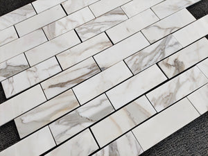 Close-up of 2×8 calacatta gold marble-patterned tiles on a surface