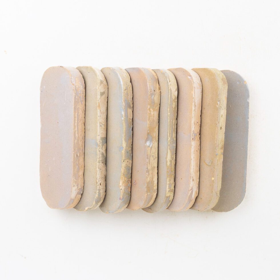 Set of eight zellige mosaic tiles with different color tones on a white background