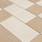 Angled close-up of alternating ivory and beige textured porcelain tiles highlighting swirl and linear surface details.