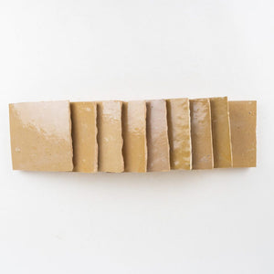 Row of amber-gold zellige square tiles on a white background