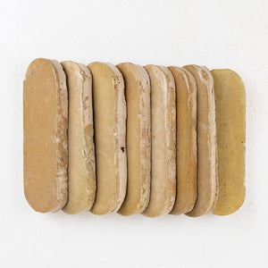 Row of Amber color zellige tiles with varying grits on a white background