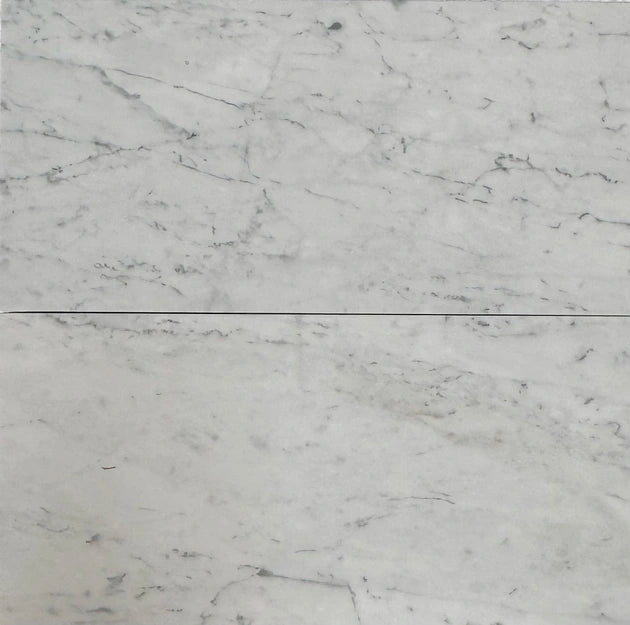 Close-up of White Carrara marble tiles with gray veining, highlighting their polished finish and suitability for upscale interiors.