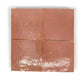 Four square terracotta zellige tiles in a deep red color with a glossy finish, showing handcrafted irregular edges.