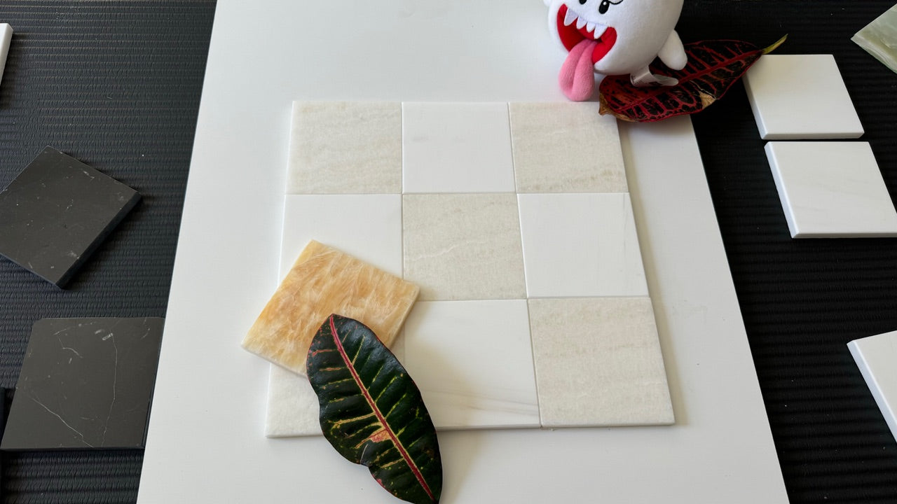 A calming checkerboard pattern featuring a mix of Bianco Dolomite and Crema Marfil tiles, accented by natural light and a striking red leaf, perfect for creating sophisticated tile designs for residential or commercial spaces.