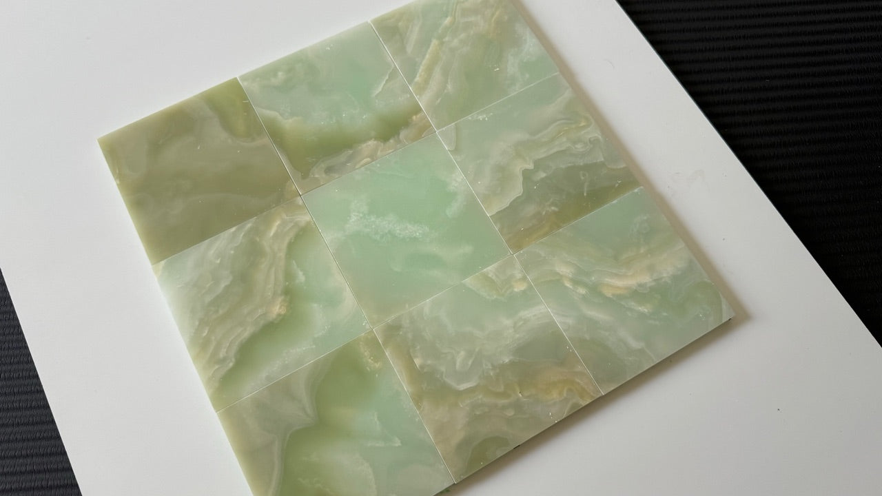 A close-up of nine Green Onyx stone tiles arranged in a smooth, seamless grid pattern. The soft green hues and natural veining of the onyx provide a luxurious feel, ideal for bathroom or kitchen tiling projects.
