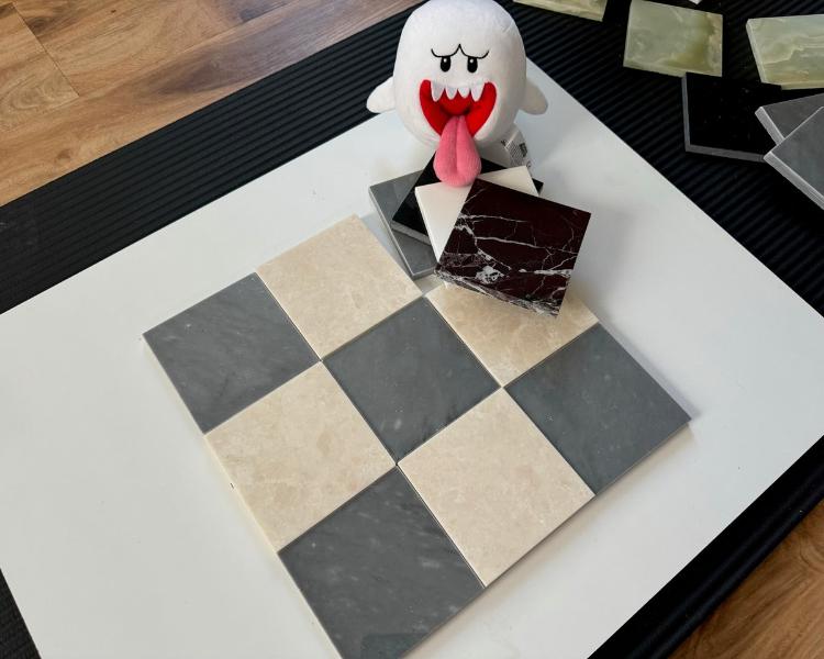 A close-up of Bardiglio Imperial blue marble and creamy beige marble tiles in a checkerboard pattern, with intricate veining and smooth finishes that create an upscale aesthetic.