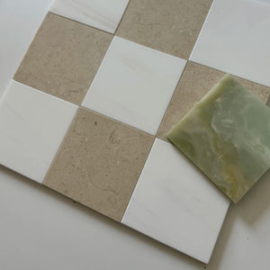 A beautifully textured combination of Crema Marfil and Bianco Dolomite tiles in a classic checkerboard layout, with an additional square of soft green onyx tile for contrast. Perfect for modern tile installations.