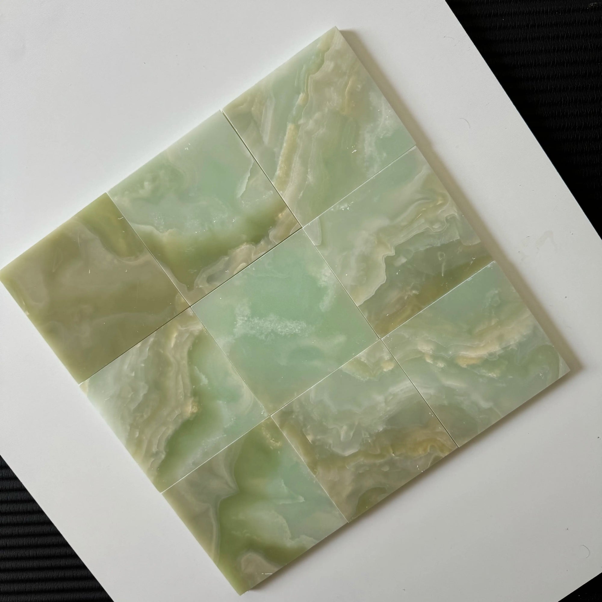 A full tile panel of Green Onyx arranged in a square grid. The soft, calming hues of green and cream in the Onyx make this natural stone tile a perfect fit for serene bathroom walls or luxurious backsplashes, adding depth and warmth to any space.