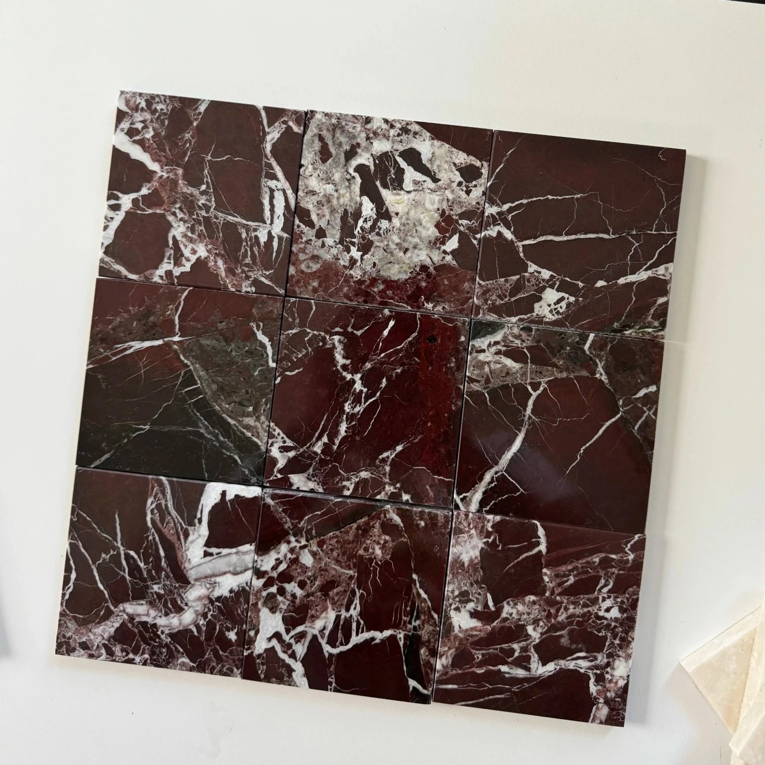 Close-up of Rosso Levanto marble tiles arranged in a grid layout. The deep red color of the marble, with bold white veining and natural stone patterns, offers a rich and dramatic look, perfect for luxurious interior spaces, including flooring, walls, and feature areas.